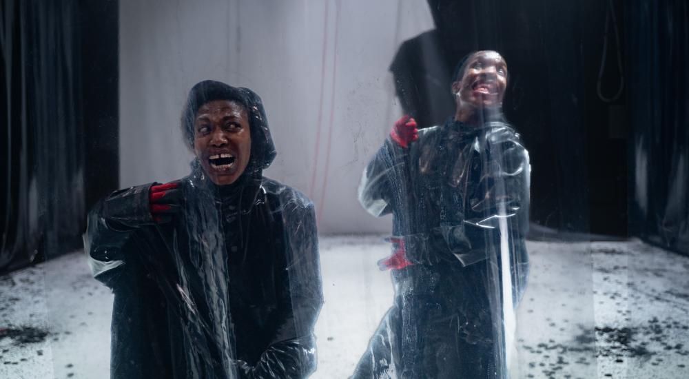 2 dancers in suits behind plastic wall