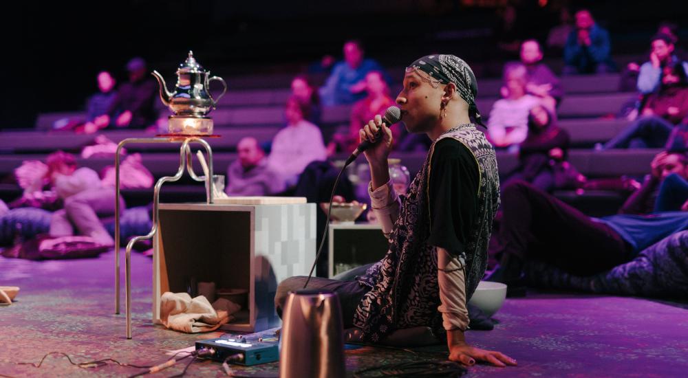 Person sitting on stage, talking in a microphone